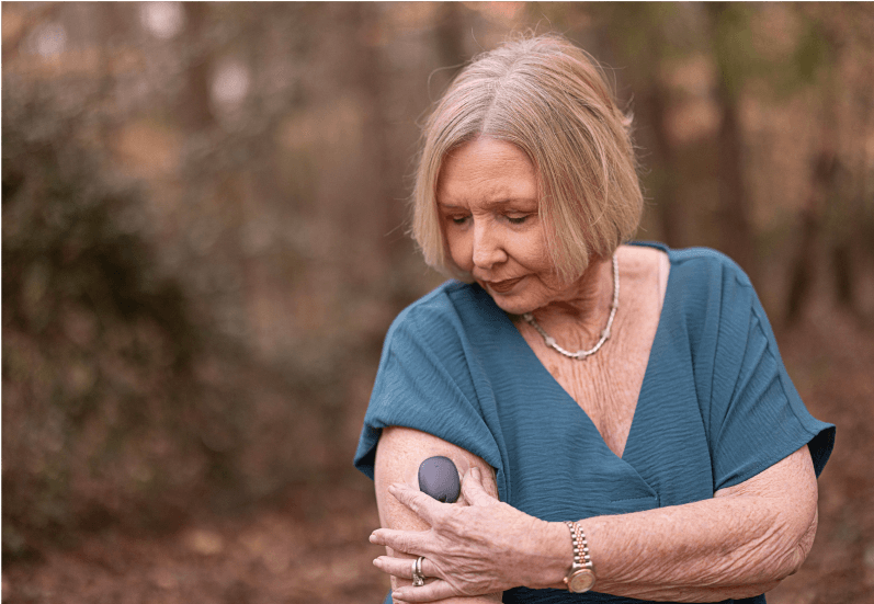 Woman applying adhesives to her Eversense CGM to secure transmitter on arm